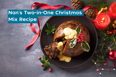 Grey slate backdrop with a Christmas pudding decorated in green and red Christmas decorations (holy, candles and ribbons)
