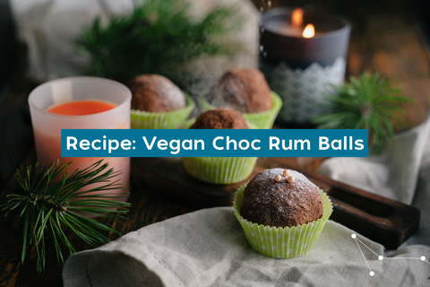 A Christmas setting on a table with linen hand towels, pine trees, candles and rum balls in small green silicone cupcake holders