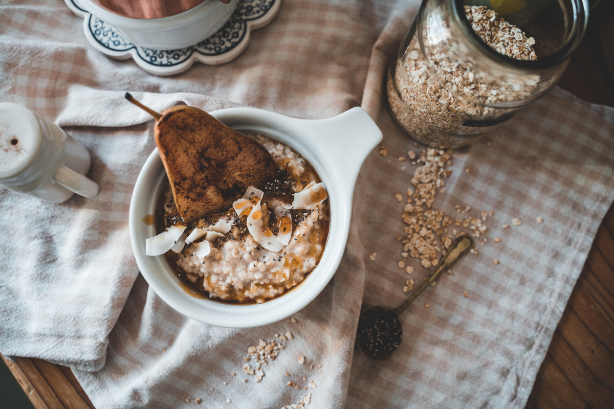 Bowl of steel cut oats with half a pear sitting in the middle of the table in a white bowl on a linen table cloth