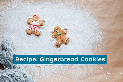 Two decorated gingerbread people laying on a bed of icing sugar